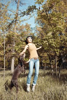 Happy woman playing with dog outdoors