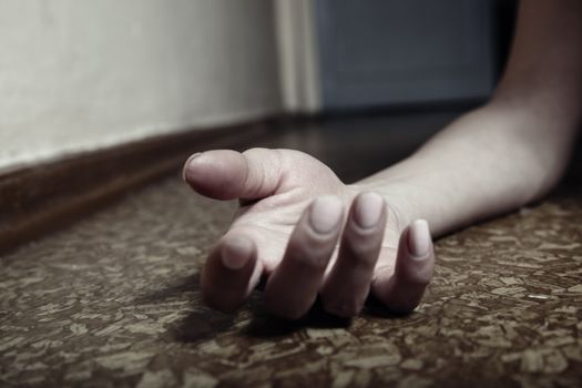 Close-up photo of the human hand laying on the floor