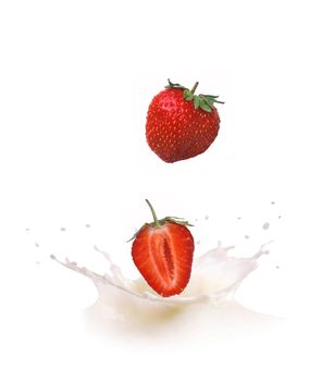 Strawberry falls into milk causing splash and drops