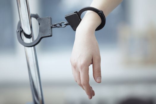 Human hand bounded to the metal pole by handcuffs