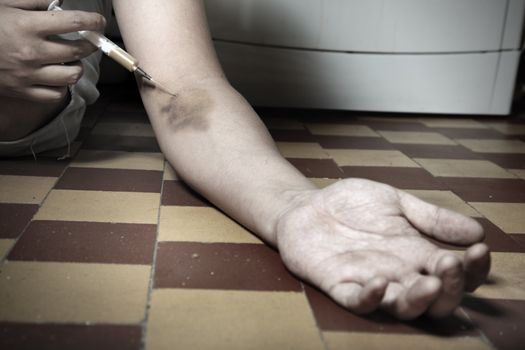 Hand of the narcotist with syringe on the floor. Artistic colors added