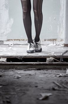 Human legs in stylish shoes standing in the ruined dirty room