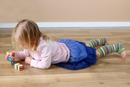 Little girl lying on her tummy building blocks
