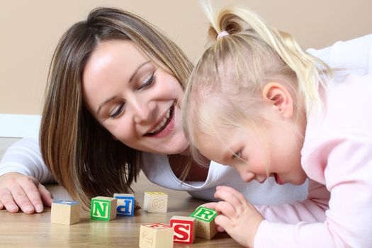 Mother and daughter playing with alphabet building blocks