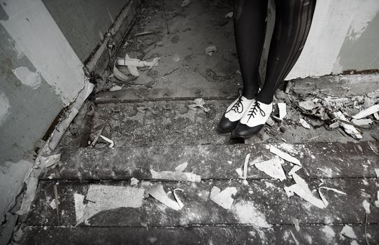 Human legs in stylish shoes standing in the ruined dirty room