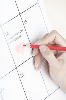 Woman hand drawing heart shape on a calendar