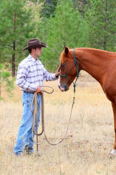Young cowboy touching his horse on his nose