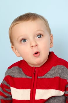 Cute blond baby wearing a red jersey against blue