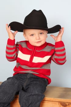 Cute blond baby wearing a red jersey against blue