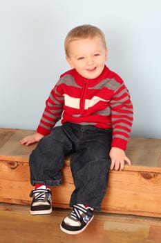 Cute blond baby wearing a red jersey against blue