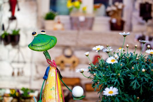 frog toy next to a pot of daisies