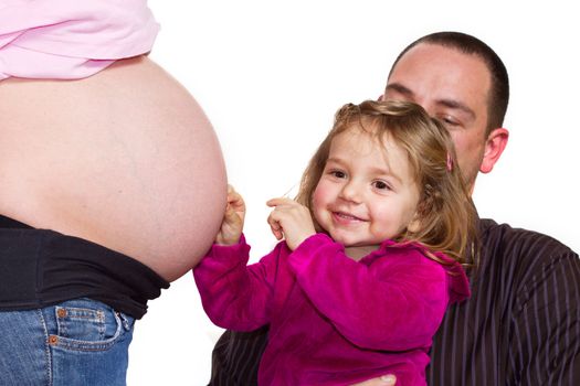 a young girl playing with her mothers pregnant belly helped by father