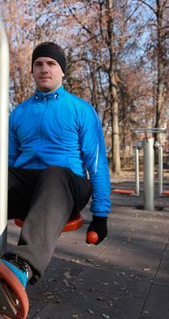 A young man doing exercise outdoors in a public park.