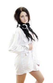 Sensual brunette girl in man's shirt with headphones. Isolated on white.