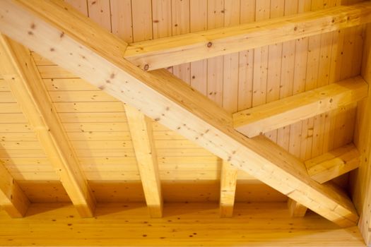 Interior architectural details of a wooden ceiling showing beams and joins extending into a corner