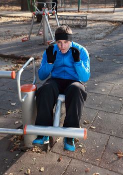 Young man doing situps outdoors in a public park.