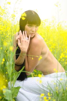 Classic beauty wearing a white dress standing in a field of yellow wildflowers.