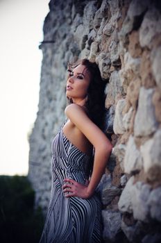 Woman Posing Against Stone Wall, oblique angle with receding perspective.