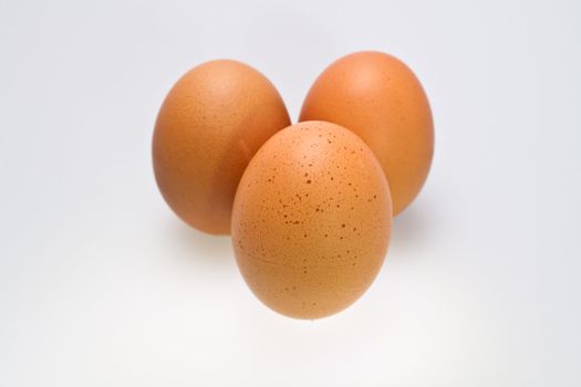 Three brown eggs isolated on white surface
