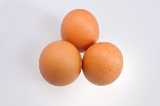 Three brown eggs isolated on white surface