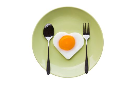 Fried egg heart and spoon on green dish