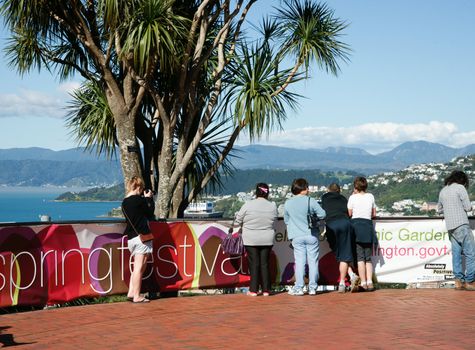 Group of tourists at top of Mount Victoria overlook the Wellington central city. Banner for the Wellington Spring Festival is erected in front of them.