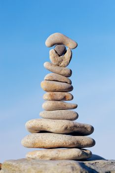 Pile of oblong pebbles in the balance on a sky background