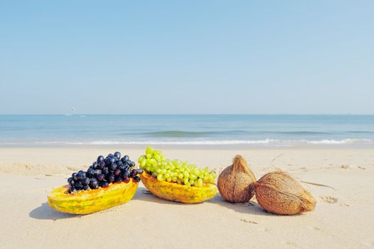 Papaya, coconut and grapes on the sandy beach