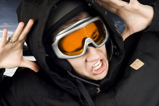 Boy dressed in snowboarding suit and helmet and googles reacting surprised on something he sees.

Studio shot.