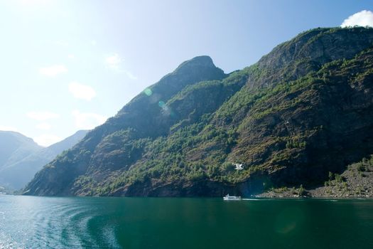 Fjord landscape in the western area of Norway, Aurlandsfjord in Sognefjord with sun flare and a ferry