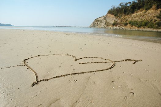 Heart with arrow shooting over drawn on a wet sandy beach