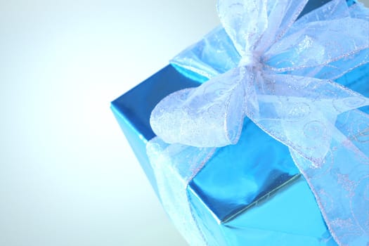 Elegant sky blue colored present with silver ribbons and bow isolated on white.