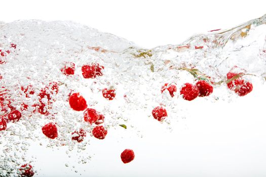 Raspberries floating in water with bubbles and waves