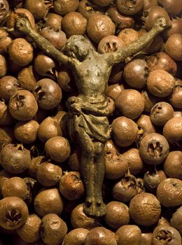 Concept shot of a crucifix of Jesus lying on a bed of rotten medlar fruits.
