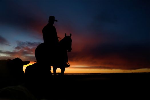 A cowboy on a hill against a sunset