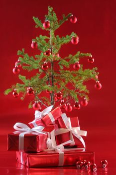 Elegant red presents under Christmas tree with deep rich red background.