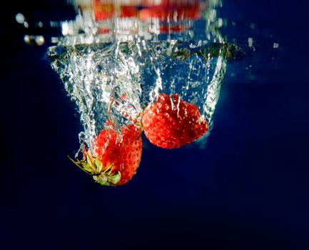 Two Strawberries splashing in water