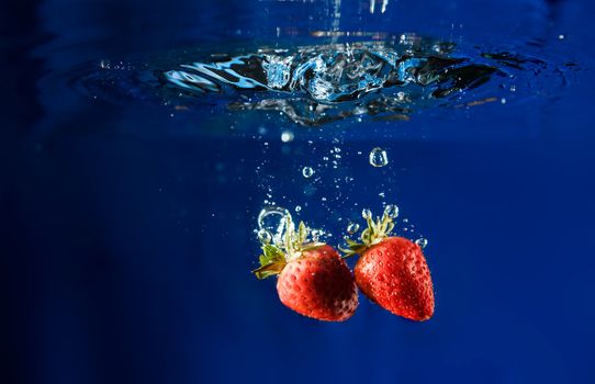 Two strawberries splashing in water