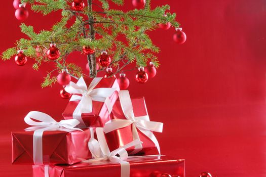 Elegant red presents under Christmas tree with deep rich red background.