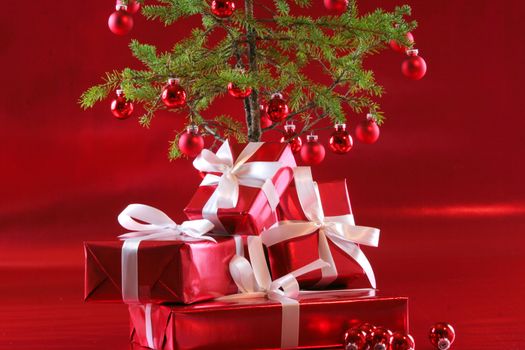 Elegant red presents under Christmas tree with deep rich red background.