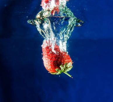 A fresh strawberry dropping in water.