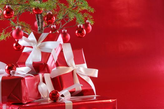 Elegant red presents under Christmas tree with deep rich red background.