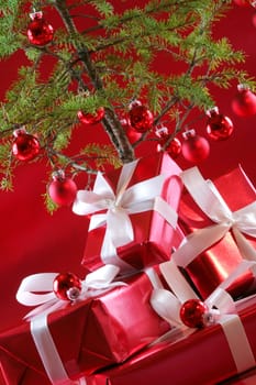 Elegant red presents under Christmas tree with deep rich red background.