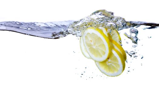 A group of lemon slices dropped in water with bubbles