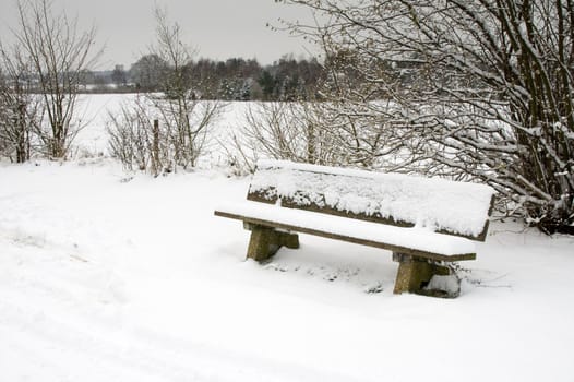 winter landscape with park bench covered with snow
