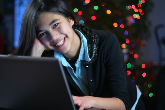 Young teen girl working on the laptop at night.