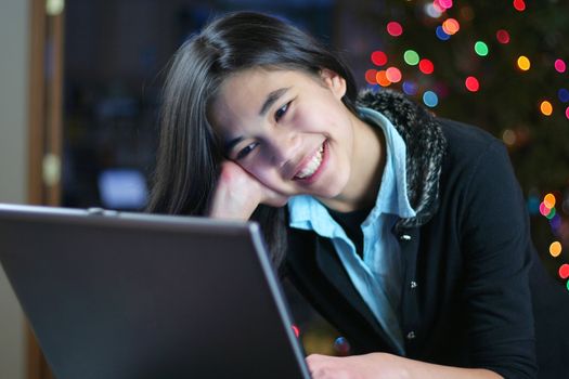 Young teen girl working on the laptop at night.