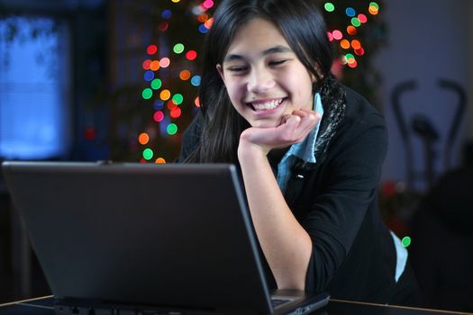 Young teen girl working on the laptop at night.