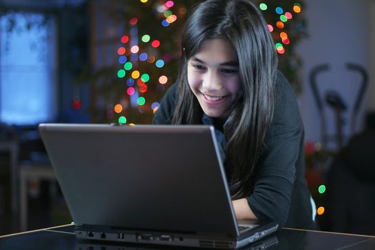 Young teen girl working on the laptop at night.