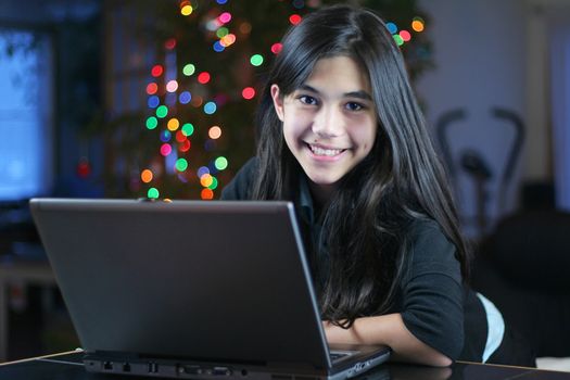 Young teen girl working on the laptop at night.